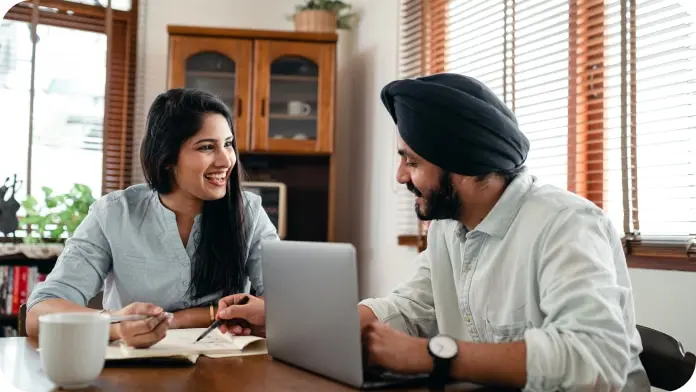 Couple smiling while looking at laptop