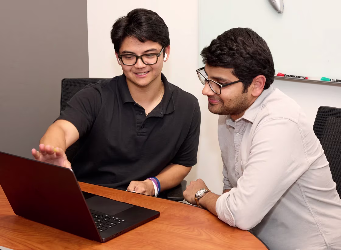 Two team members reviewing work together on a laptop