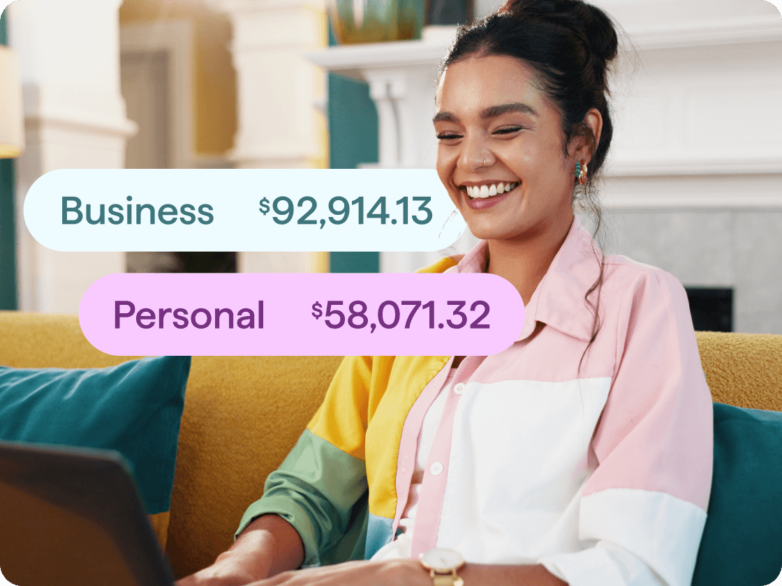 A woman is sitting on a couch working on her computer. Her Business and Personal income balances overlap the image in two bubbles.