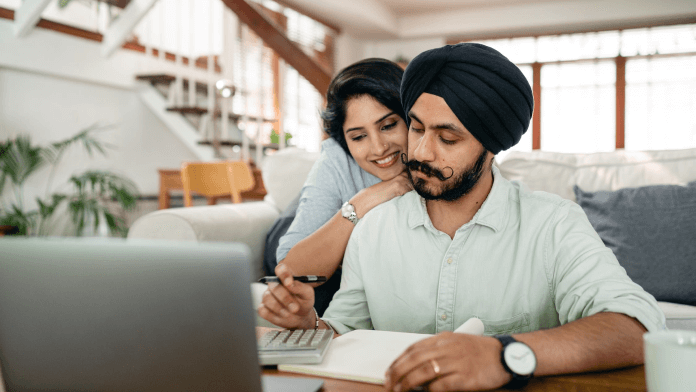 Couple discussing on future investment, while she is leaning on his shoulders, front of the laptop.