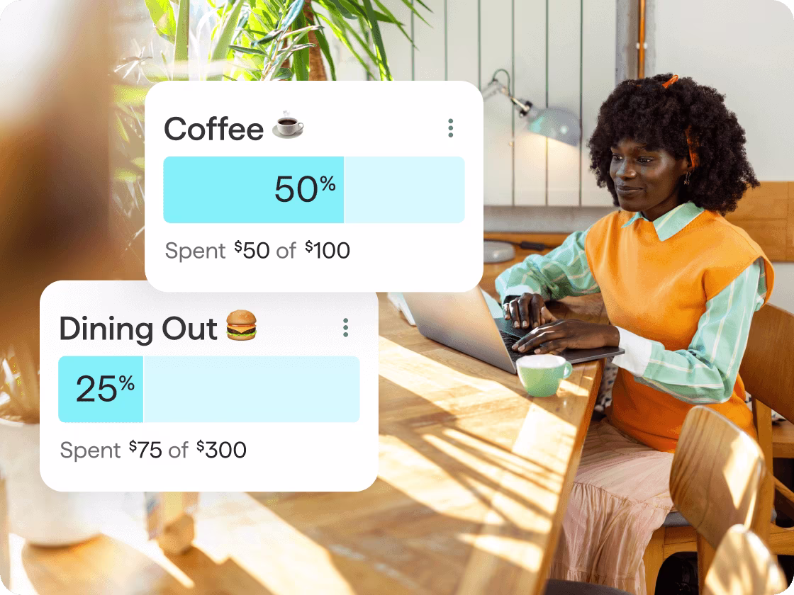 A woman is sitting at a table and reviewing her personal expenses on a computer. Overlapping the image are two bubbles showcasing her dining out expense and coffee expense.