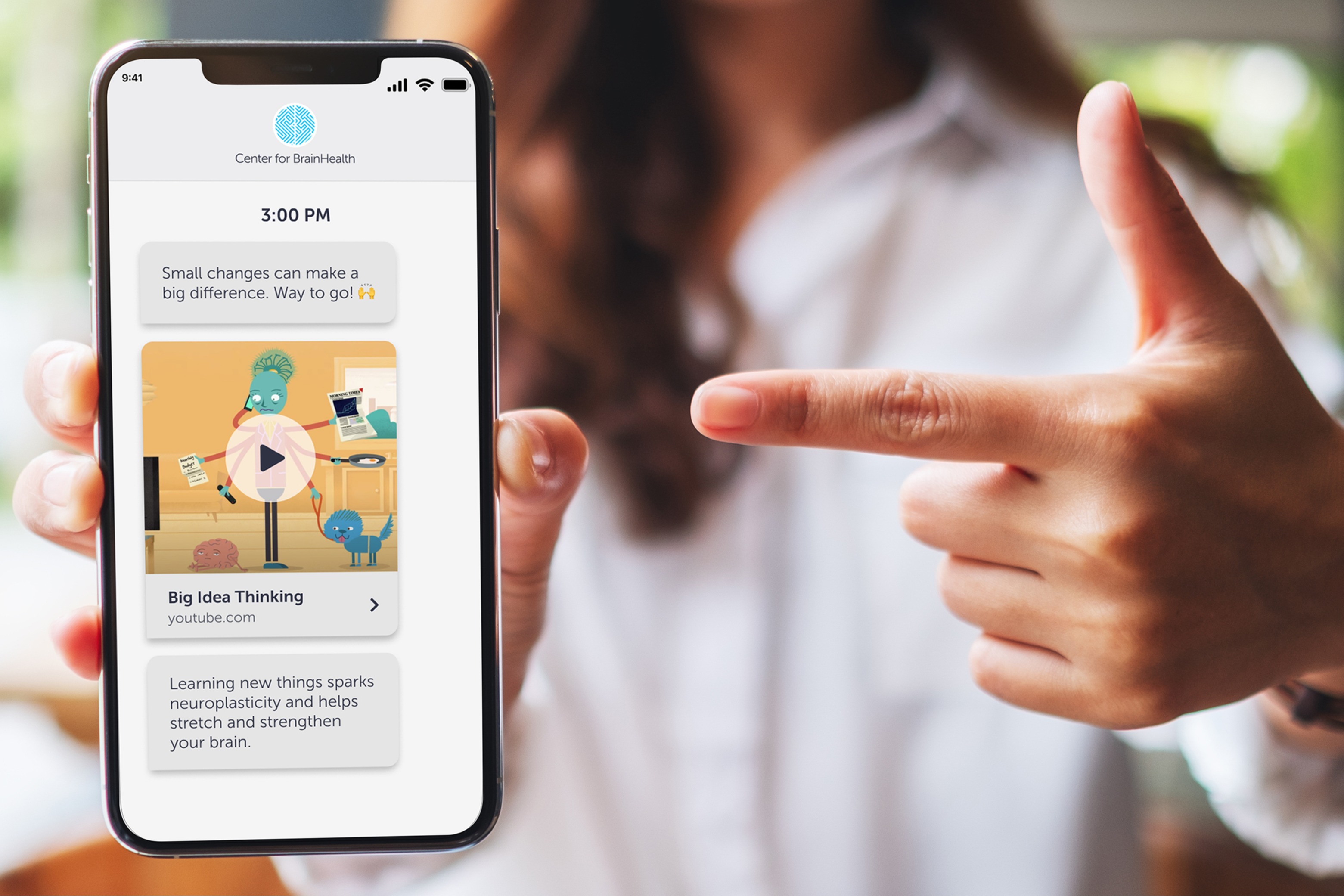 Woman pointing at a phone showing Great Brain Gain text challenge screen.