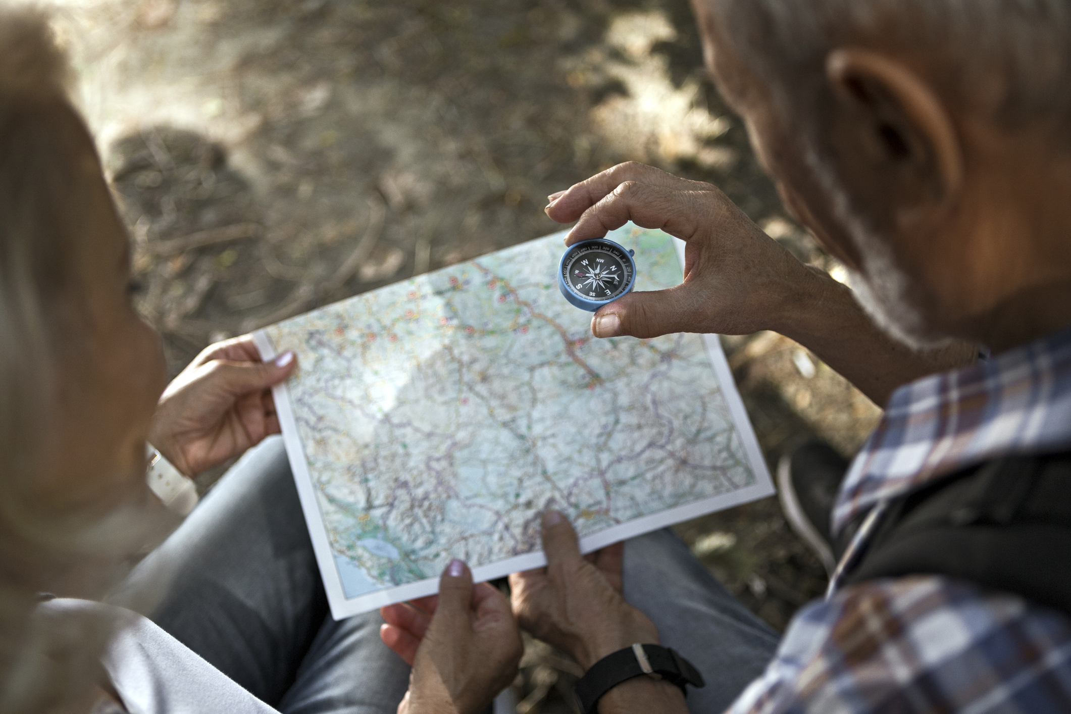A mature couple uses a map and compass to navigate their walk.