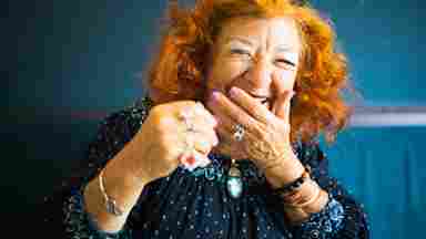 An elegant, mature woman laughs heartily at a joyful joke.