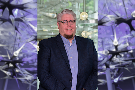 Aaron Tate hero with BPI neuron sculpture in purple light. Head of Emerging Tech.