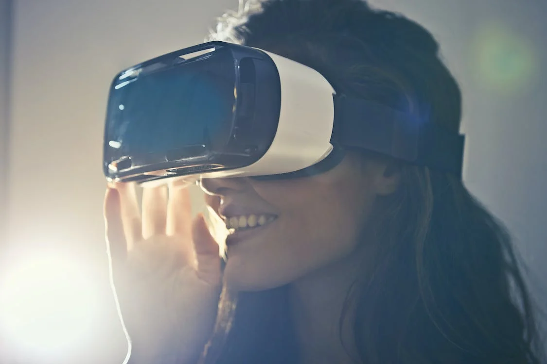 A women facing left with a VR headset on. She is smiling. 
