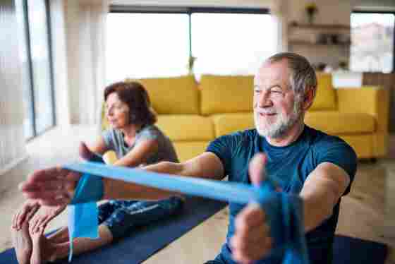 A happy senior couple with elastic bands indoors at home, doing exercise on the floor. IStock#: 1173306369