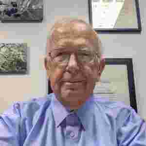 Michael Merzenich in a light blue dress shirt in office. Distinguished Collaborator