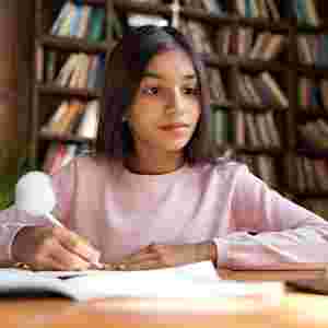 A young female student is studying while looking at the tablet. Child. Kid. Youth.