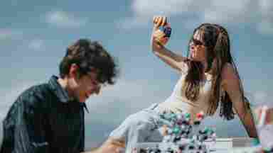 Two students study outdoors; a girl holds a colorful brain model while a boy writes notes, with molecular models on the table.