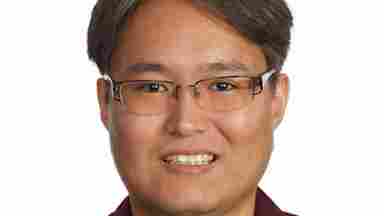 A headshot of Kihwan Han, Ph.D. who is wearing a burgundy shirt and standing in front of a white background.