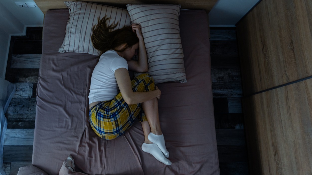 A college student sleeps soundly in fetal position as morning light comes in the window. 