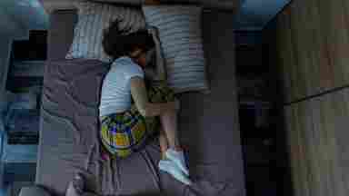 A college student sleeps soundly in fetal position as morning light comes in the window.