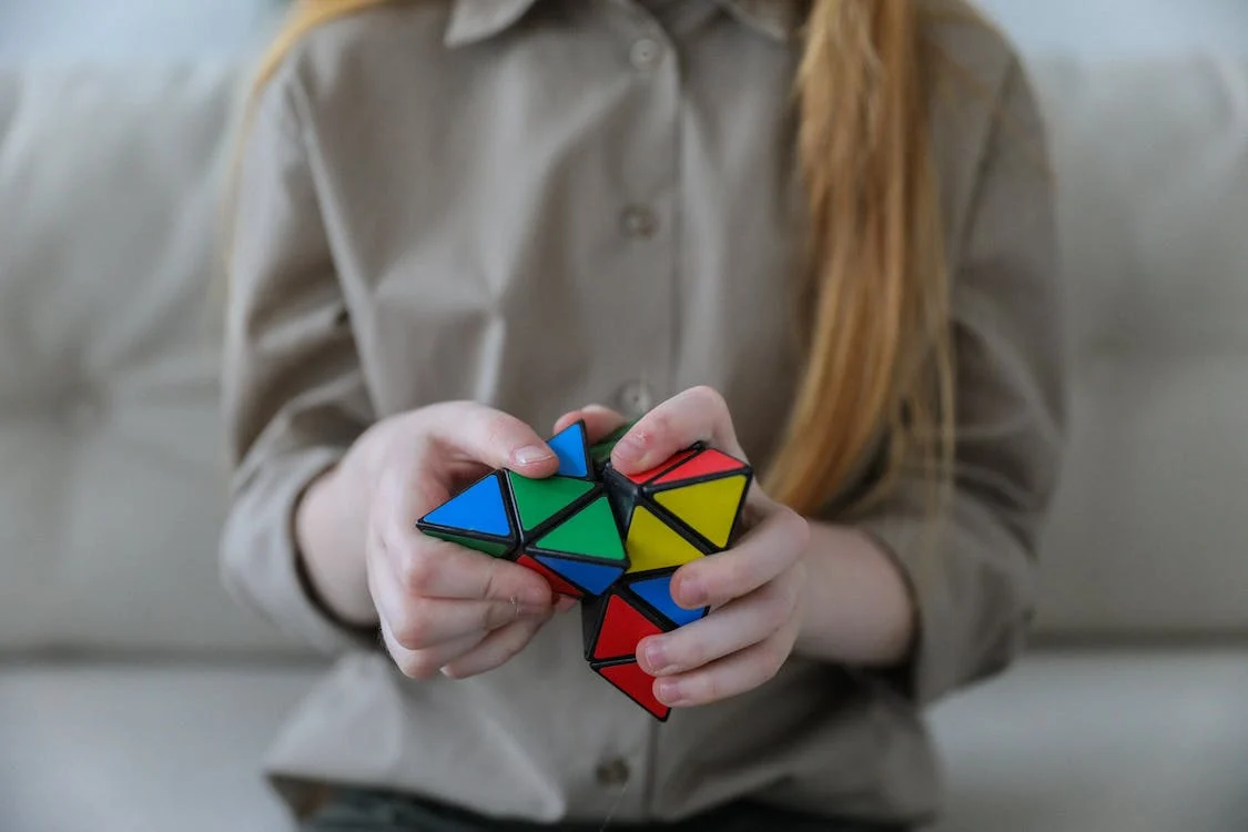 A girl with long blonde hair is solving a triangle puzzle