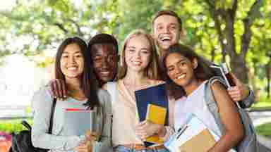A diverse group of teenage students (college or high school) are holding school books and smiling to the camera.