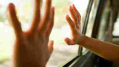 A child's hands pressed against the car window during a road trip.