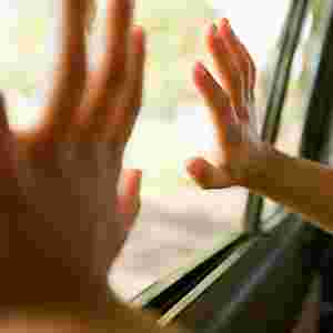 A child's hands pressed against the car window during a road trip.