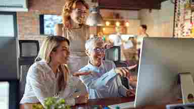 Two younger women being mentored by senior-aged colleague.