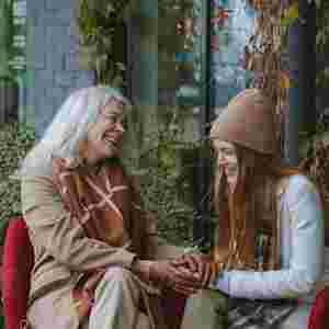 Senior woman talking and smiling with young woman outdoors.