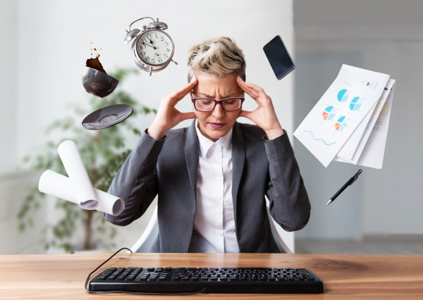 A stressed businesswoman is surrounded by floating office objects indicating her numerous tasks of the day. 