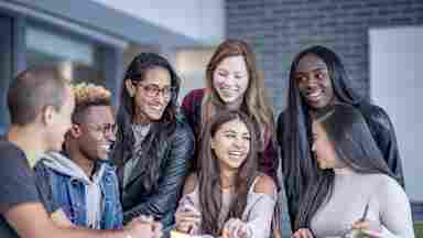 A diverse group of happy college students sitting around a table. iStock-1067477990