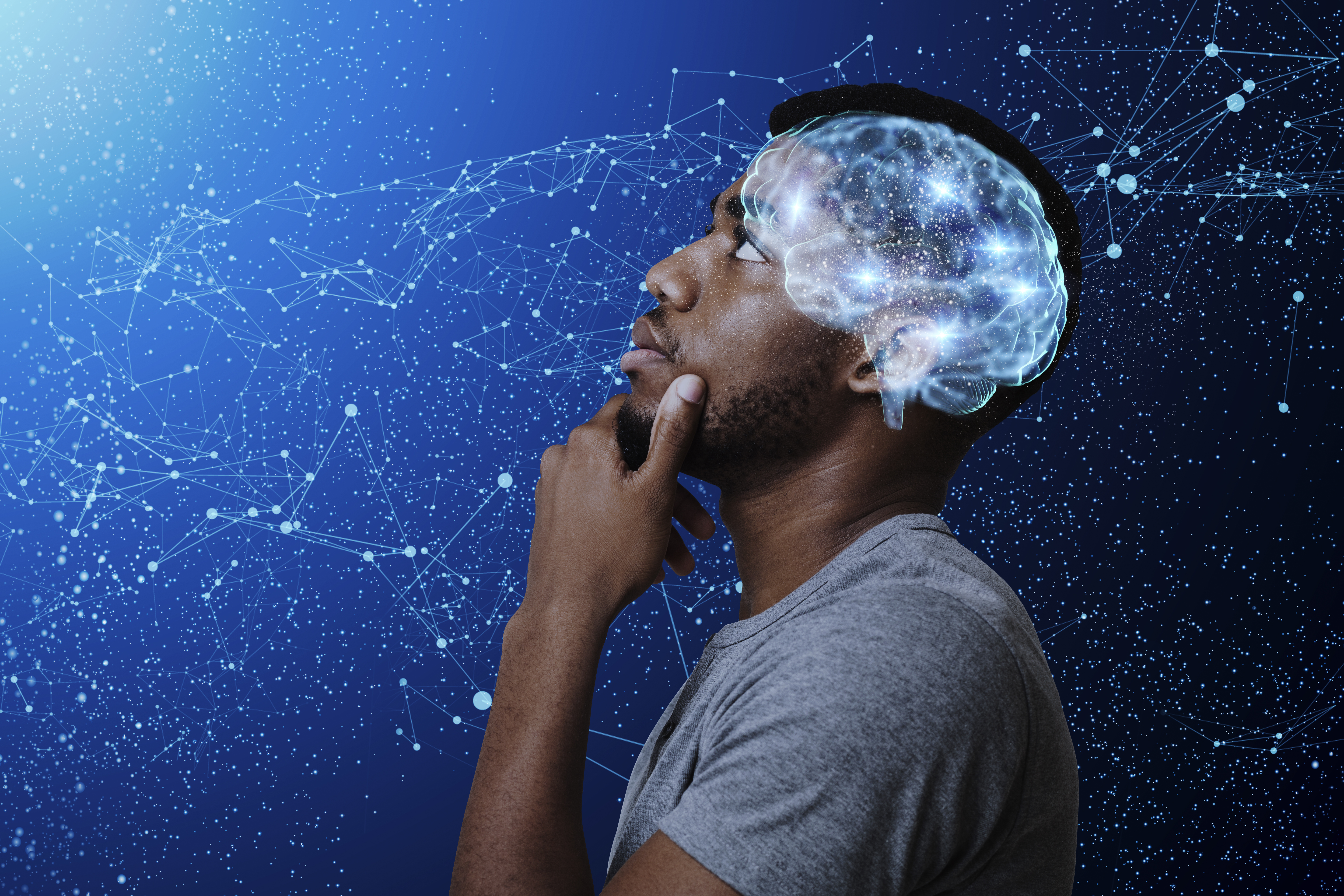 A thoughtful, Black man looking up and pondering a starlit sky. There is a blue outline of his brain with starts contained inside of it.