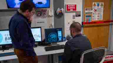 Over the shoulder shot of Sergey (left) and Jason (right) looking at brain imaging.