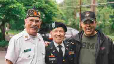 Three happy elderly men are wearing Air Force uniforms while smiling into the camera.