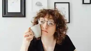 Curly haird women holding a coffee mug.