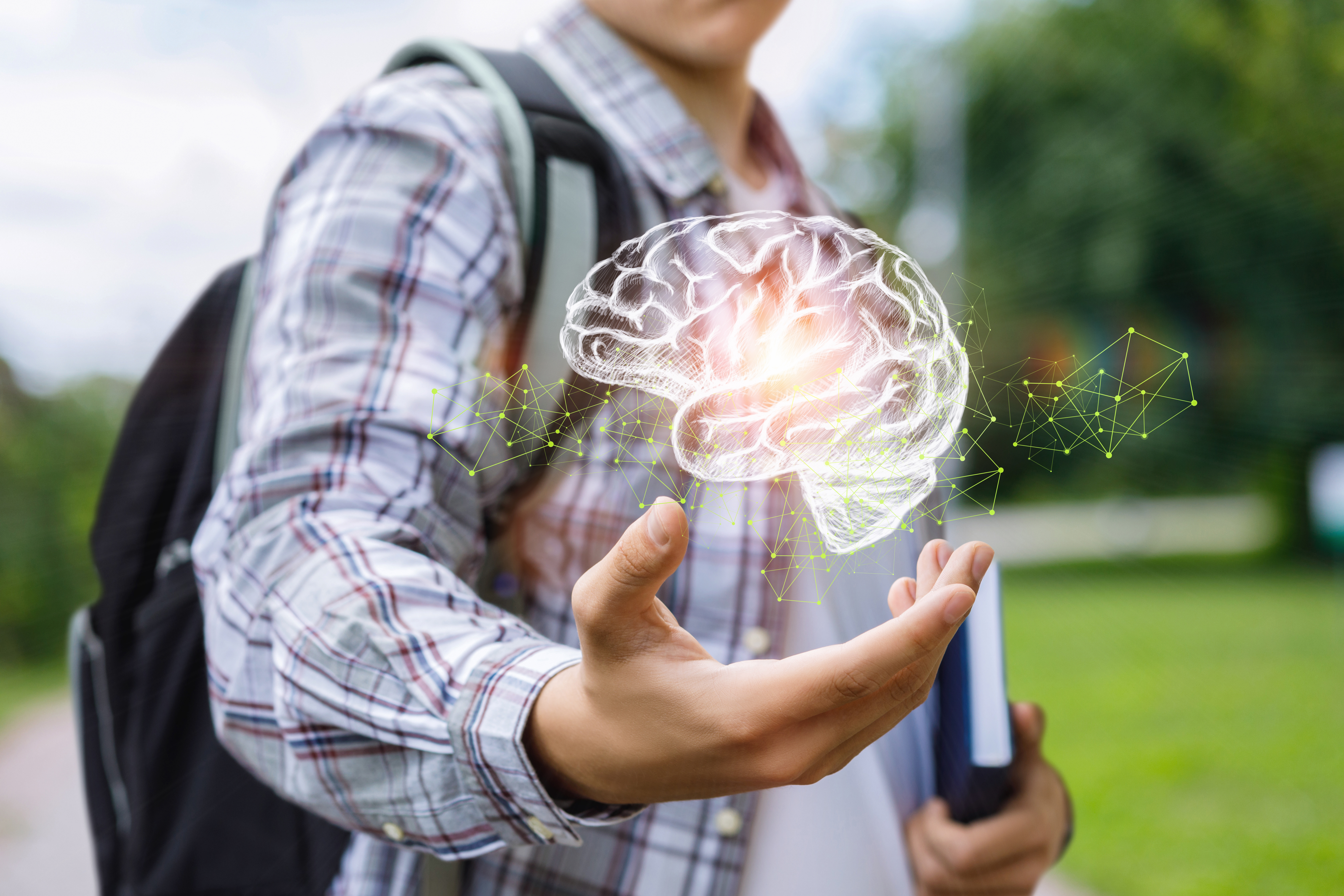 A student with a backpack holds a glowing digital brain hologram with green network connections floating above their hand.