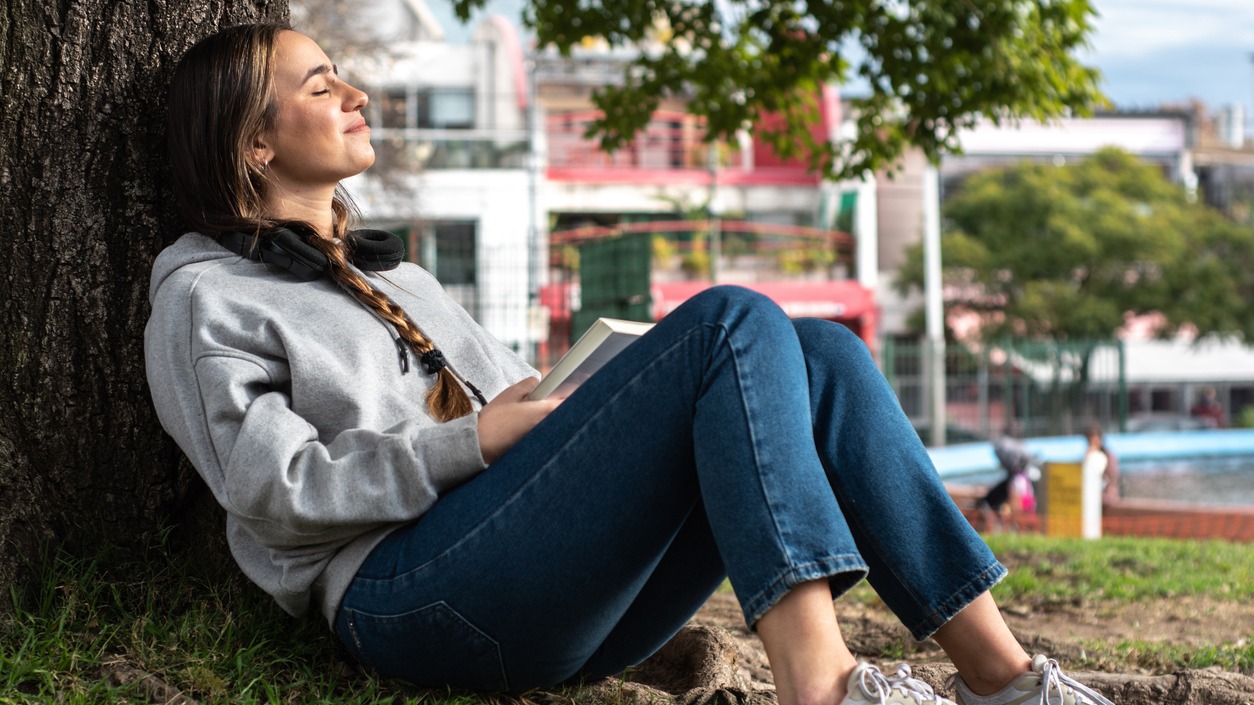 A college student rests under a tree in the community park.