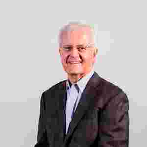 A headshot of David Jacobs for the board webpage; he is wearing a dark patterned blazer and a light blue shirt.