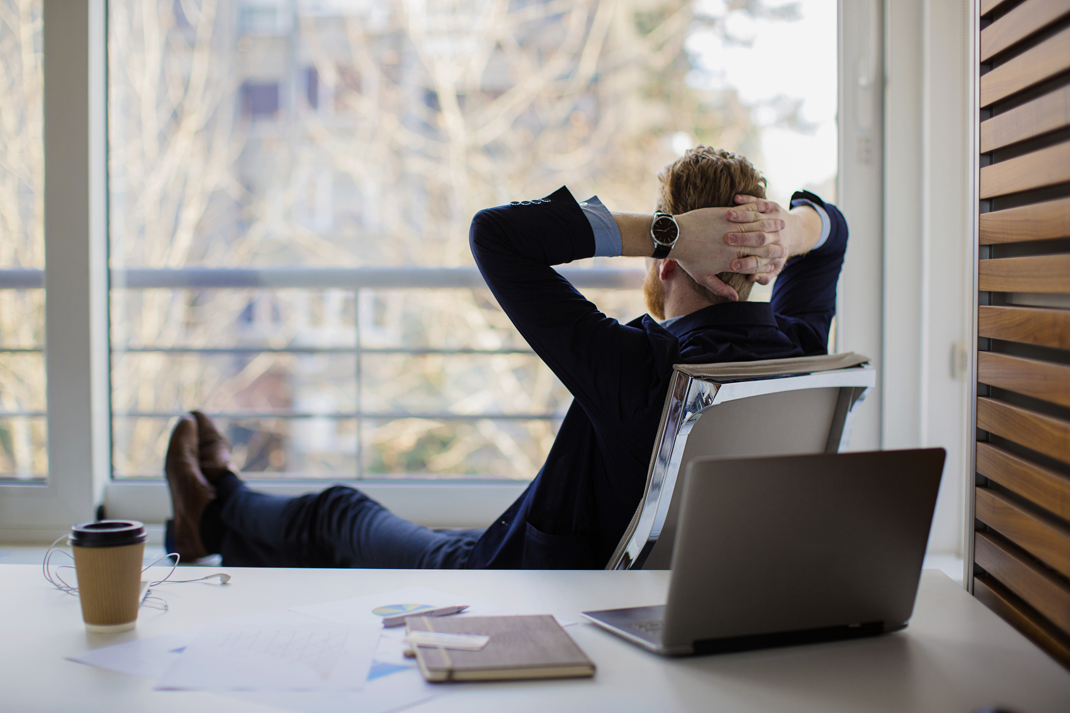 Businessman resting in an office and looking out the window at nature.