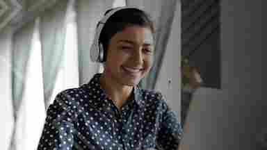 Happy woman wearing headphones working on laptop.