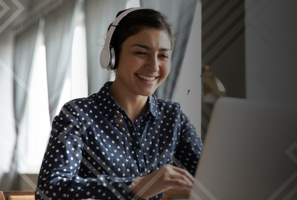 Happy woman wearing headphones working on laptop. IStockID# 1218223744.