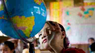 A child studies a globe of Earth in a classroom.