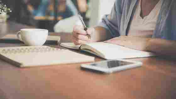 A student focuses on writing in a bright, relaxed location.