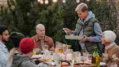 Multi generational family eating dinner outdoors.