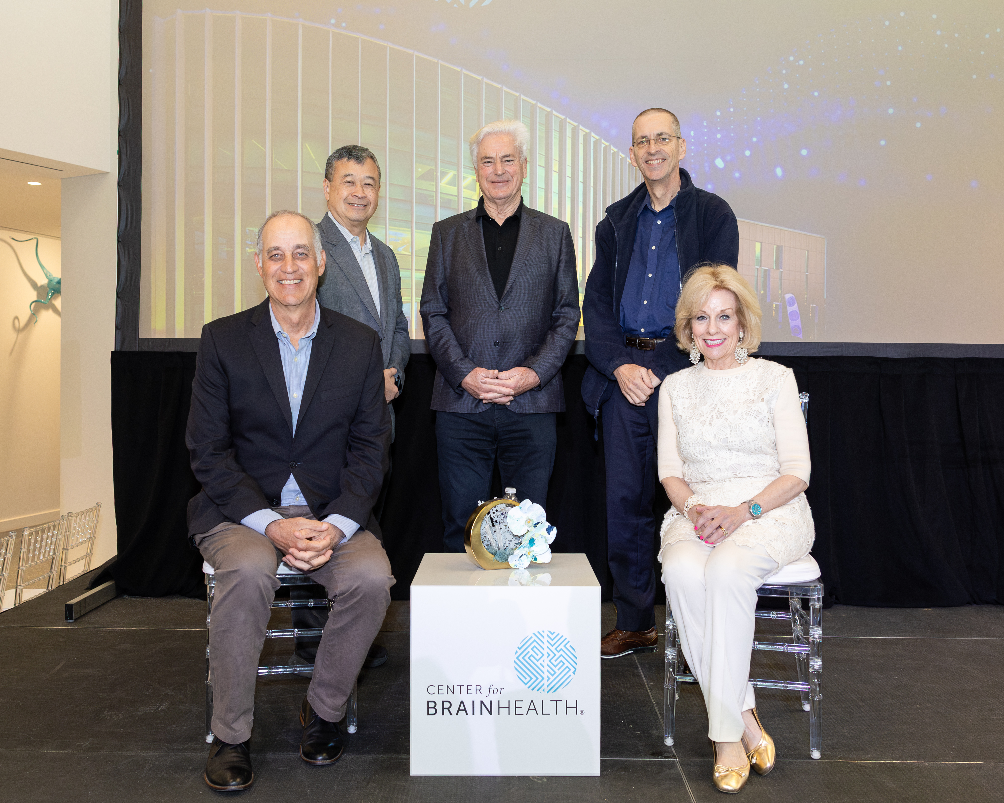 The Society’s founding members sitting on stage at BrainHealth Week 2026 around cube: Top row Mark D’Esposito, MD, Russell Foster, PhD, FRS, CBE (not pictured), Sandra Bond Chapman, and back row Geoffrey Ling, MD, PhD,  Ian Robertson, PhD, and PhD, Vince Calhoun, PhD.

