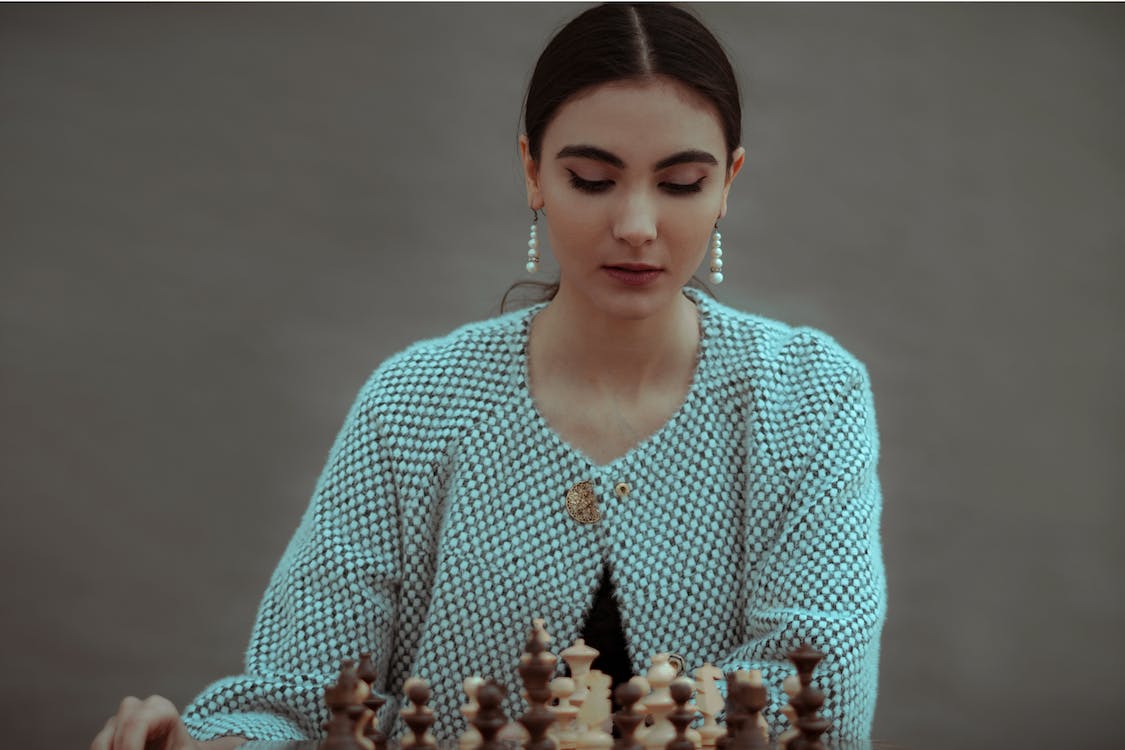 A women stares at a chess board.