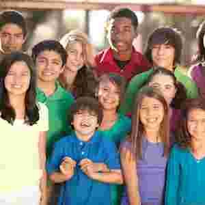 A diverse group of youths/children smiling into the camera.