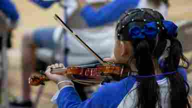 Young girl playing a violin in a school.