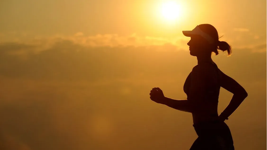 Woman with white sun visor enjoying an athletic run. 