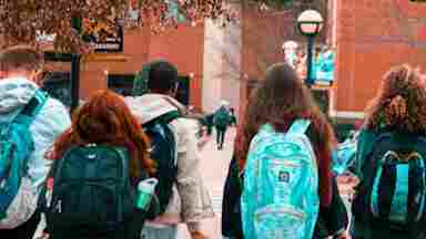 Students wearing backpacks walking away from the camera.