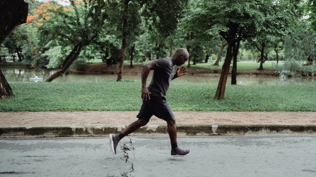 Man of color in a gray t-shirt and back shorts working out.