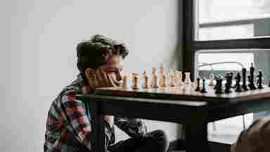 Adolescent concentrating on the pieces on a chess board