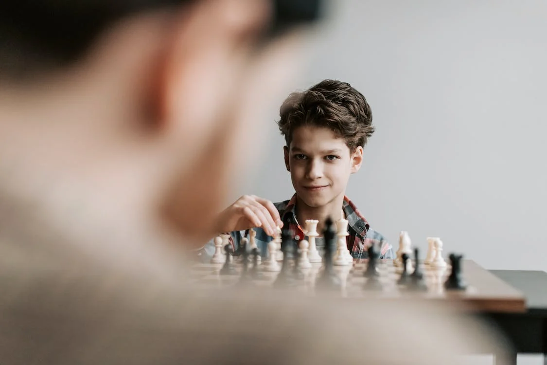Over the shoulder shot of a man and child playing chess