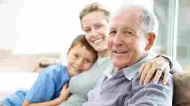 A happy elderly man and his family smiling at the camera.