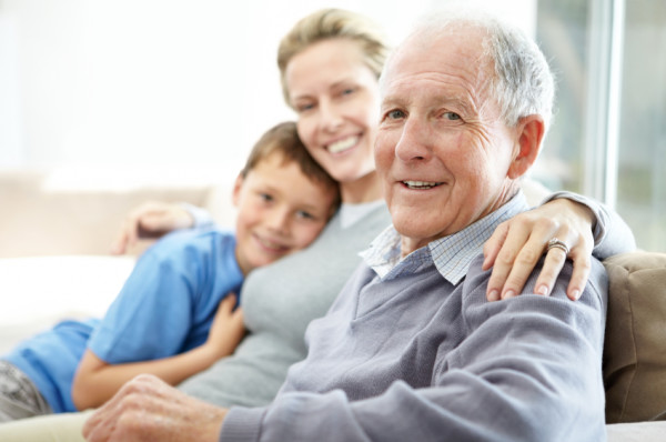 Happy family with focus on elderly man smiling, looking at the camera. Older. White.