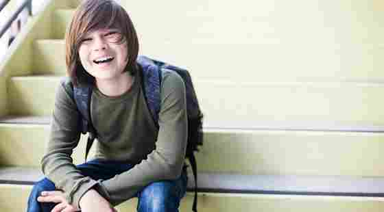 A young male student smiling into the camera on a staircase. 